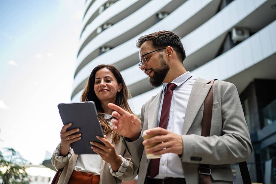 Two real estate agents talk in front of a building