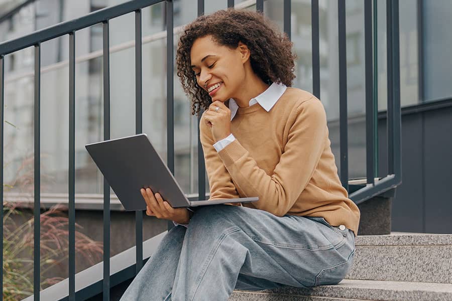 A woman using a laptop while sitting outside on a staircase