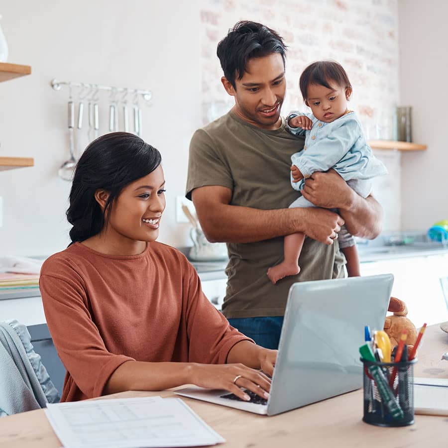 A family using a laptop at the kitchen counter