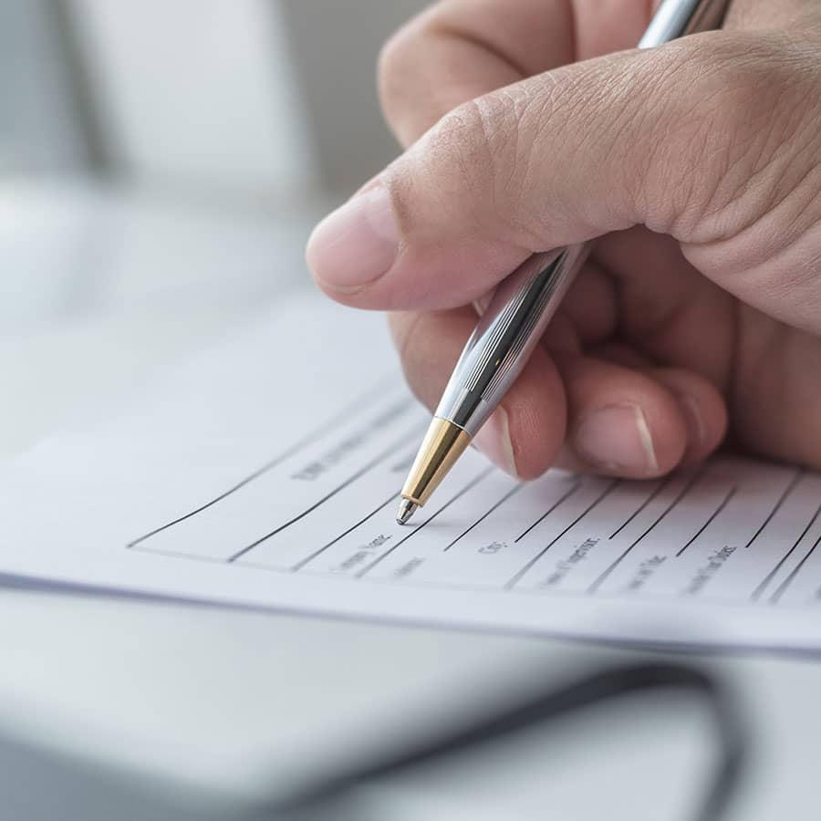 A hand holding a pen and filling out a form