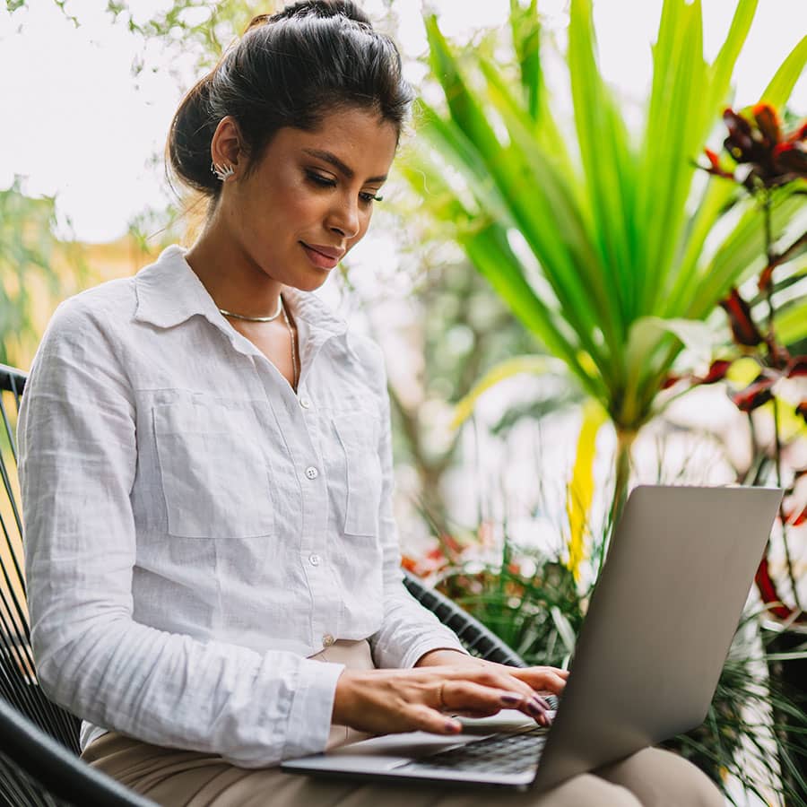 A woman on a laptop in a tropical setting