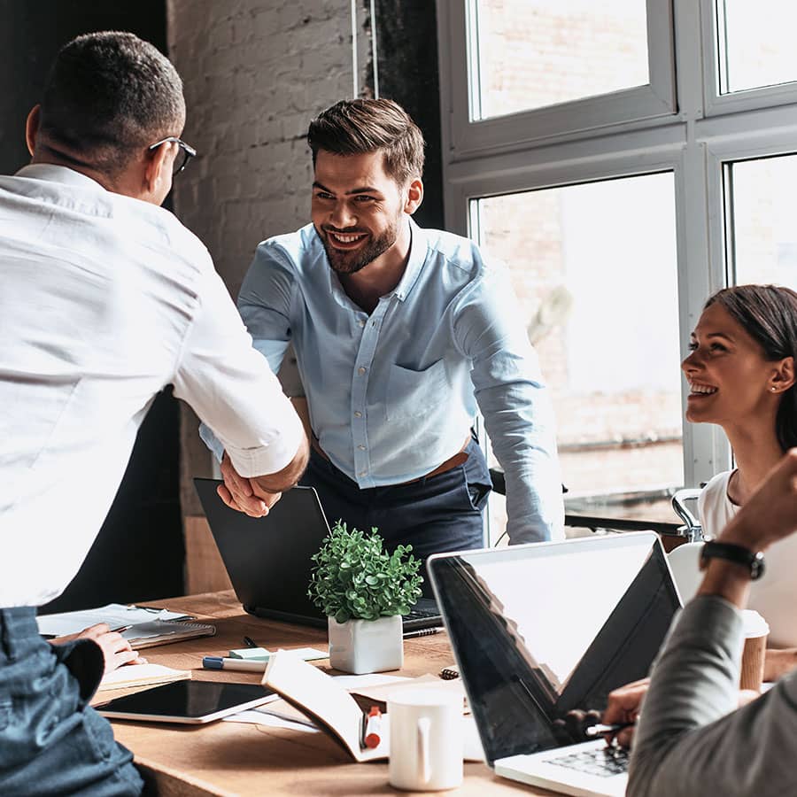 Coworkers shaking hands over a conference room table
