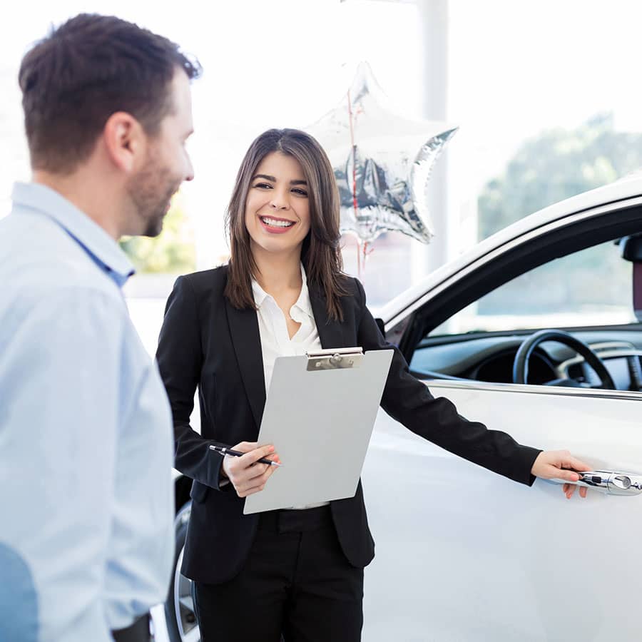 A saleswoman shows a man a new car