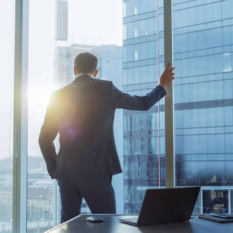 A business man gazes out his corner office window
