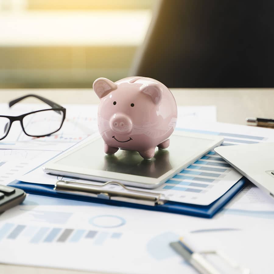 A piggybank sitting on a pile of documents on a desk