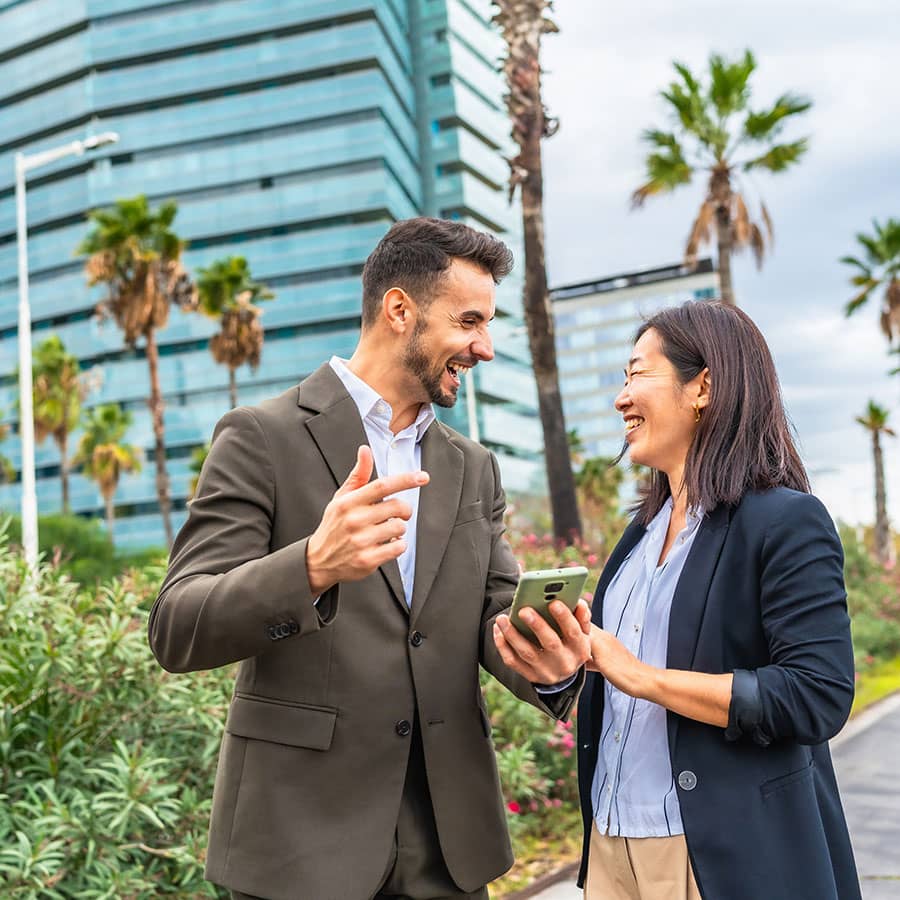 Two people talk business outside a building
