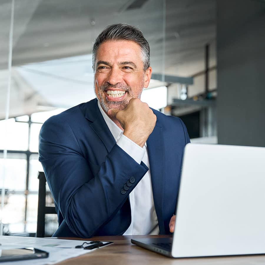 A business man sits at his desk and smiles