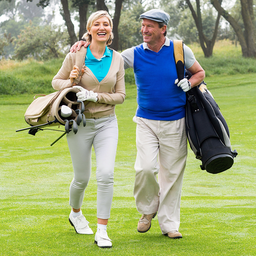 A wealthy couple walks on a golf course